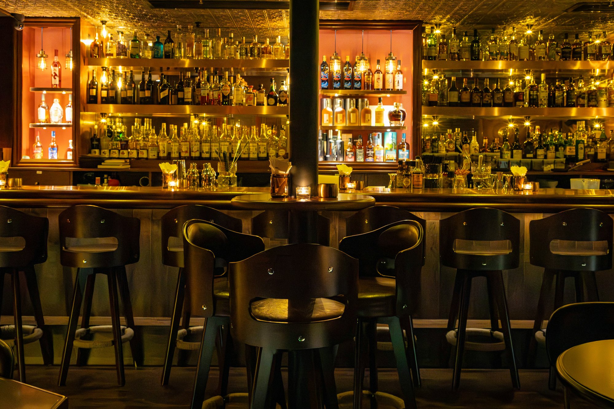 Bar im Halbdunkel mit Hockern und beleuchteten Flaschenregalen