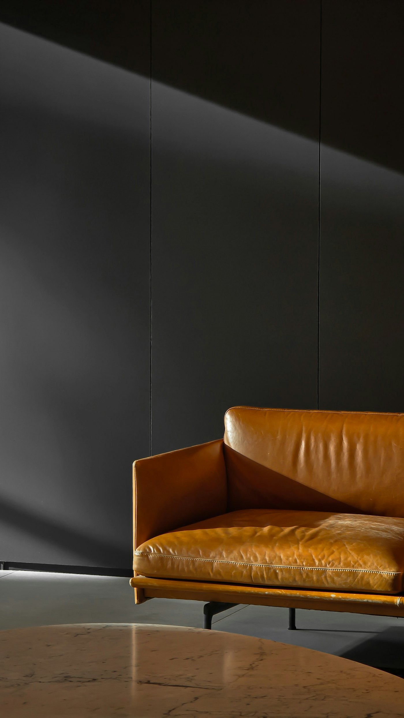 Ledersofa vor einer dunklen, ruhigen Wand