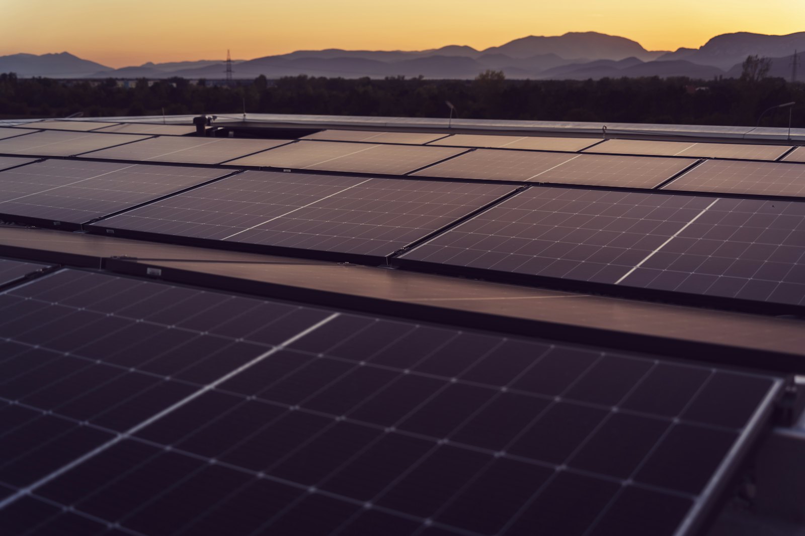 Dach mit Solarmodulen in der Abenddämmerung, dahinter Berge